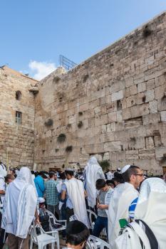 JERUSALEM, ISRAEL - OCTOBER 12, 2014: The area in front of Western Wall of  Temple filled with people. Crowd of faithful Jews wearing prayer shawls. Morning autumn Sukkot