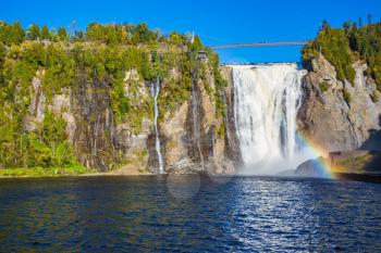 The concept of active and cultural tourism. The magnificent rainbow plays in falls splashes. The blue lake and powerful waterfall Montmorency in Montmorency Falls Park, in Quebec