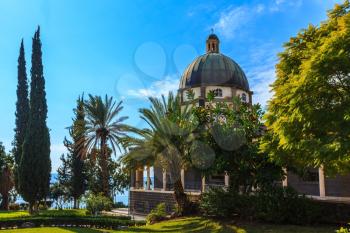 Israel, the shores of Lake Kinneret. Catholic monastery and small church Mount Beatitudes. Dome and colonnade surrounded by cypress and palm trees.