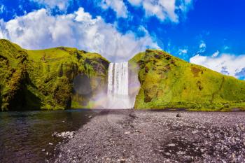  Iceland, waterfall Skogafoss summer, clouds of mist. Huge picturesque waterfall flowing from under a giant glacier