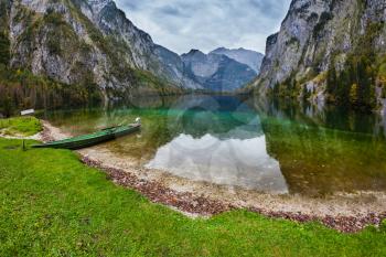 The magic blue lake Obersee in Bavarian Alps. Concept of active tourism. Fishing boat with a small engine in shallows of the lake