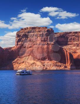 Scenic huge artificial water basin of the Colorado River, USA. Lake Powell is surrounded by magnificent sandstone hills. Walk on white boat on a sunny day