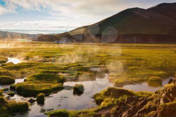 Above the source of thermal water steam rises. White nights in Iceland. Sunrise Park Landmannalaugar
