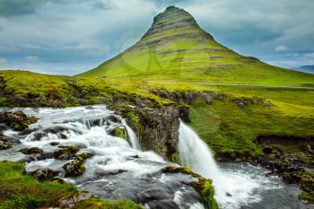  The concept of exotic and extreme tourism. The most famous mountain in Iceland is Kirkjoufell. At the foot of the mountain cascading waterfalls Kirkjoufellfoss