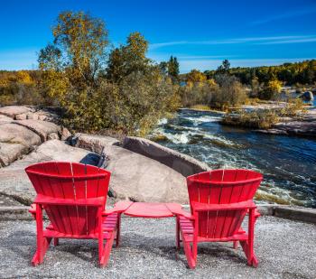 Lovely place to relax. Two red beach chairs on the riverbank. Winnipeg River, Old Pinawa Dam Park. The concept of ecological and recreational tourism