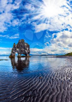 Basalt rock - monster Hvitsercur ocean low tide. Concept of northern extreme tourism. Soft northern sun of Iceland at sunset