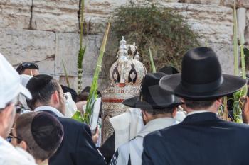 JERUSALEM, ISRAEL - OCTOBER 12, 2014: Morning autumn Sukkot. The area in front of Western Wall of  Temple. Crowd of Jewish worshipers in white wearing prayer shawls. Sefer Torah in magnificent case ke