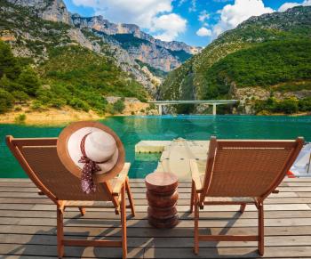  Two wooden chairs and straw hat on the platform at lake Verdon. Travel to Provence