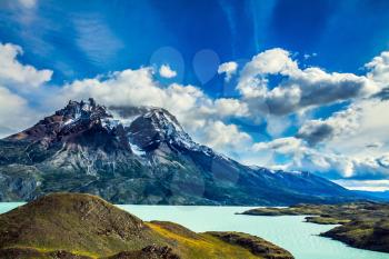 Strong wind drives the clouds. The concept of active and extreme tourism. Azure lake Pehoe between rocks Los Kuernos. National Park Torres del Paine. Travel in Chile