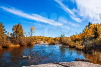 Tranquil scenery in the autumn Old Pinawa Dam Park. Thin cirrus clouds and foam water rapids on the Winnipeg River. Trend of travel Around the World