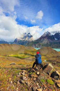 Strong winds in the Chilean Patagonia. National Park Torres del Paine, Lake Pehoe. Woman - photographer barely held on the stone, photographing nature