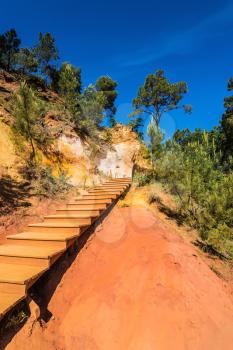 Steps for tourists on a steep slope. Unique red and orange hills in the province of Languedoc - Roussillon, France