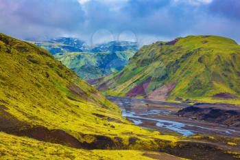 Picturesque basalt hills covered with green grass and moss-polar. Streams from melting glaciers flowing down the canyon. Canyon Pakgil in Iceland