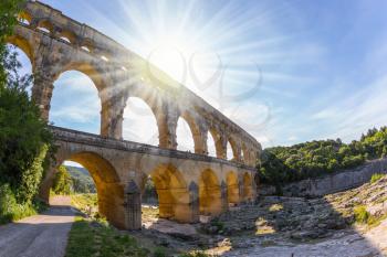 The bridge was built in Roman times on the river Gardon. Three-tiered aqueduct Pont du Gard - the highest in Europe. Provence, setting sun shines in sky