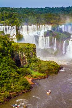  Small boats deliver tourists to waterfalls. Grandiose complex of waterfalls Iguazu Falls National Park. The concept of extreme and exotic tourism