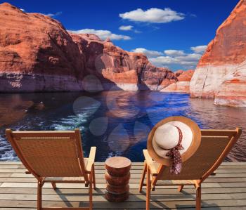 Waves from the boat dissect the lake Powell on the river Colorado. Aft vessels cost two chaise lounges. On a back of one the elegant straw women's hat hangs