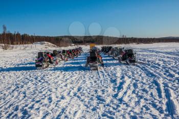 The first trip on snowmobiles in special suits. Travel to Lapland. Winter fairy tale in a sunny frosty day. The concept of active and extreme tourism