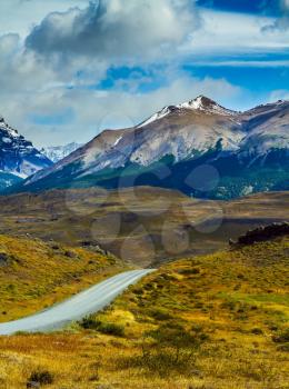 The gravel road goes into the distance. Mountains and rocks in Torres del Paine National Park. Summer in the south of Chile. The concept of active and extreme tourism