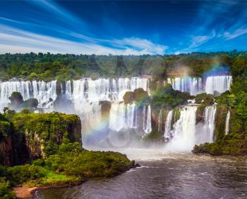 Several waterfalls from Iguazu Falls. Powerful two-stage waterfall creates a watery dust and a rainbow. The concept of exotic and extreme tourism