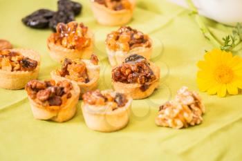 Professional baking. Background -prune. Small portioned tartlet cakes with filling of nuts and dried fruits