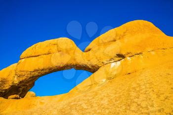 Stone arch of Spitzkoppe. Natural group of smooth bald granites among the Namib Desert, Namibia. Concept of extreme and ecological tourism
