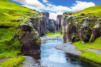 Steep vertical cliffs surround the stream of very cold water. Fantastic canyon in Iceland - Fyadrarglyufur. The concept of active northern tourism