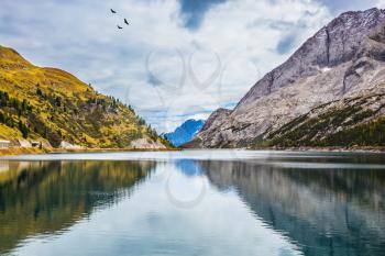 The concept of ecological and extreme tourism. The magic and harmony of the Dolomites. Glacial lake with clear cold water. Mountain Lake Lago di Fedaia, Dolomites