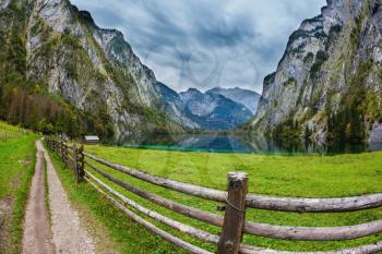 The Bavarian Alps. The magic blue lake Obersee and the fenced footpath to it. Concept of active tourism and ecological tourism