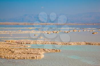 Hot summer day at the famous seaside resort on the Dead Sea, Israel. The shallow sea is covered with evaporated salt. The concept of medical and ecological tourism 