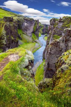 Fantastic canyon in Iceland - Fyadrarglyufur. Steep vertical cliffs surround the stream of very cold water. The concept of active northern tourism