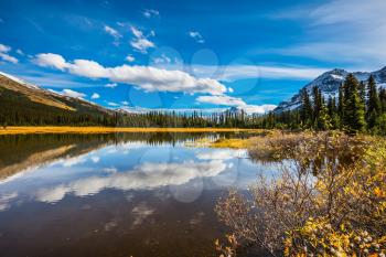Sky and clouds reflected in the smooth water in the lake. Rocky Mountains on a sunny autumn day. The concept of ecotourism