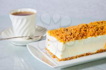  Gorgeous white cheesecake, sprinkled with sweet crumbs. Professional bakery. The background is  porcelain cup with tea 