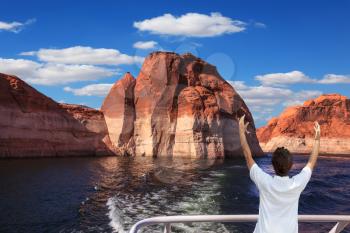 The elderly woman in white aft boats is delighted with the nature. The artificial lake Powell on the river Colorado, USA. The lake it is surrounded with picturesque coast from orange sandstone