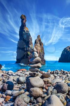 Stone pyramid - troll on a pebble beach. Volcanic island of Madeira in the Atlantic Ocean. Three huge scenic rocks. Concept of exotic and ecological tourism