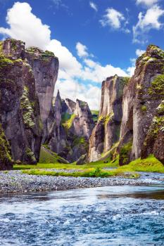 Magic beauty canyon of tales and legends in Iceland - Fyadrarglyufur. Steep cliffs, overgrown with green moss, surrounded by a very fast river with cold water