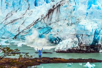 Patagonia. Woman - tourist is standing in front of a blue ice wall. Unique lake and glacier Perito Moreno. The concept of  exotic and extreme tourism