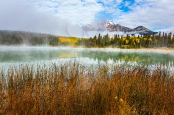 Pyramid Mountain among fog and clouds. Patricia Lake among the pines. Rocky Mountains in Canada. The concept of ecotourism