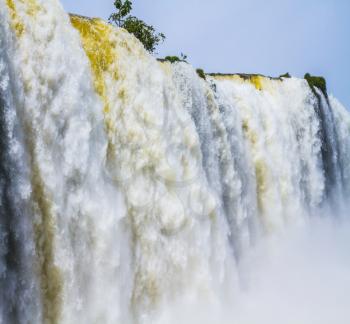 Water splashes and fog over Iguazu Falls in South America, on the border of three countries. Concept of active and extreme tourism