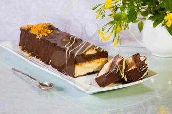 Delicious cheesecake with white and brown chocolate. The background is spoon and vase with flowers. Professional bakery