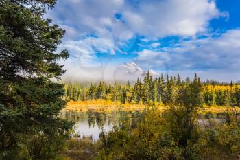 Patricia Lake among the pines. Pyramid Mountain among fog and clouds. Rocky Mountains in Canada. The concept of ecotourism