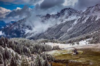 The magnificent landscape of the Dolomites in the snow. Evergreen forests in the valley covered with the first snow