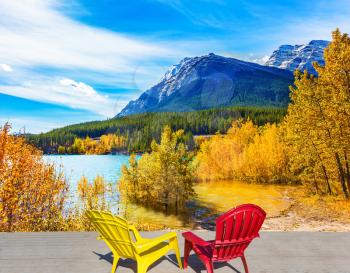 Indian summer in Rocky Mountains of Canada. Two comfortable loungers by the Abraham lake with turquoise water. Concept of ecological and active tourism