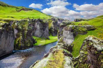 Magic beauty canyon in Iceland - Fyadrarglyufur. Steep cliffs, overgrown with green moss, surrounded by river with cold water