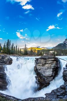The bubbling waterfall of Athabasca. Clear evening in Jasper National Park. Cold blue water at sunset. The concept of extreme and ecological tourism