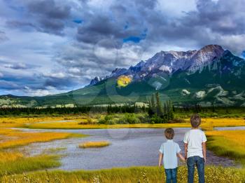 Two lovely boys admire the beauty of mountains and lakes. Magnificent landscape in the Rocky Mountains. The concept of ecological and active tourism