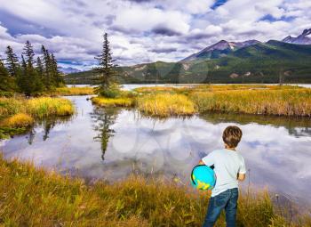 Trip to the Indian summer. Handsome boy with a globe in the Rocky Mountains. The concept of ecological and active tourism