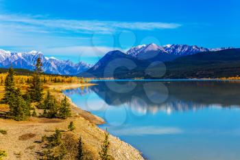 Rocky Mountains are reflected in the smooth turquoise water of the Abraham lake. Warm September. Concept of ecological and active tourism