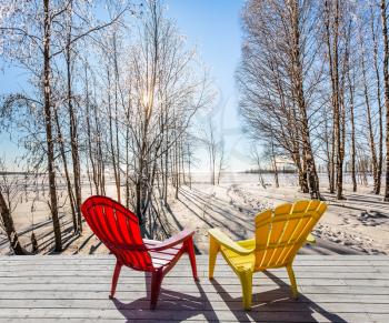 Comfortable red and yellow plastic chaise lounges for relaxing in forest.  Sunset in the Arctic. The sun shines low over the horizon. The concept of extreme and ecotourism tourism