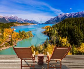 Two comfortable wooden deckchairs by the Abraham lake. Warm autumn in the mountains of Canada. Concept of ecological and active tourism