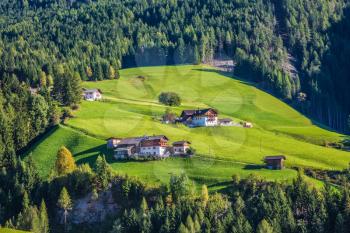 Rural pastoral in the Val de Funes, Dolomites. Warm autumn day. Charming chalet on a green grassy slope of the mountain. The concept of ecological tourism
